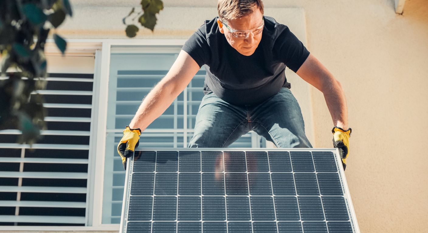Technician installing a solar panel on a house roof